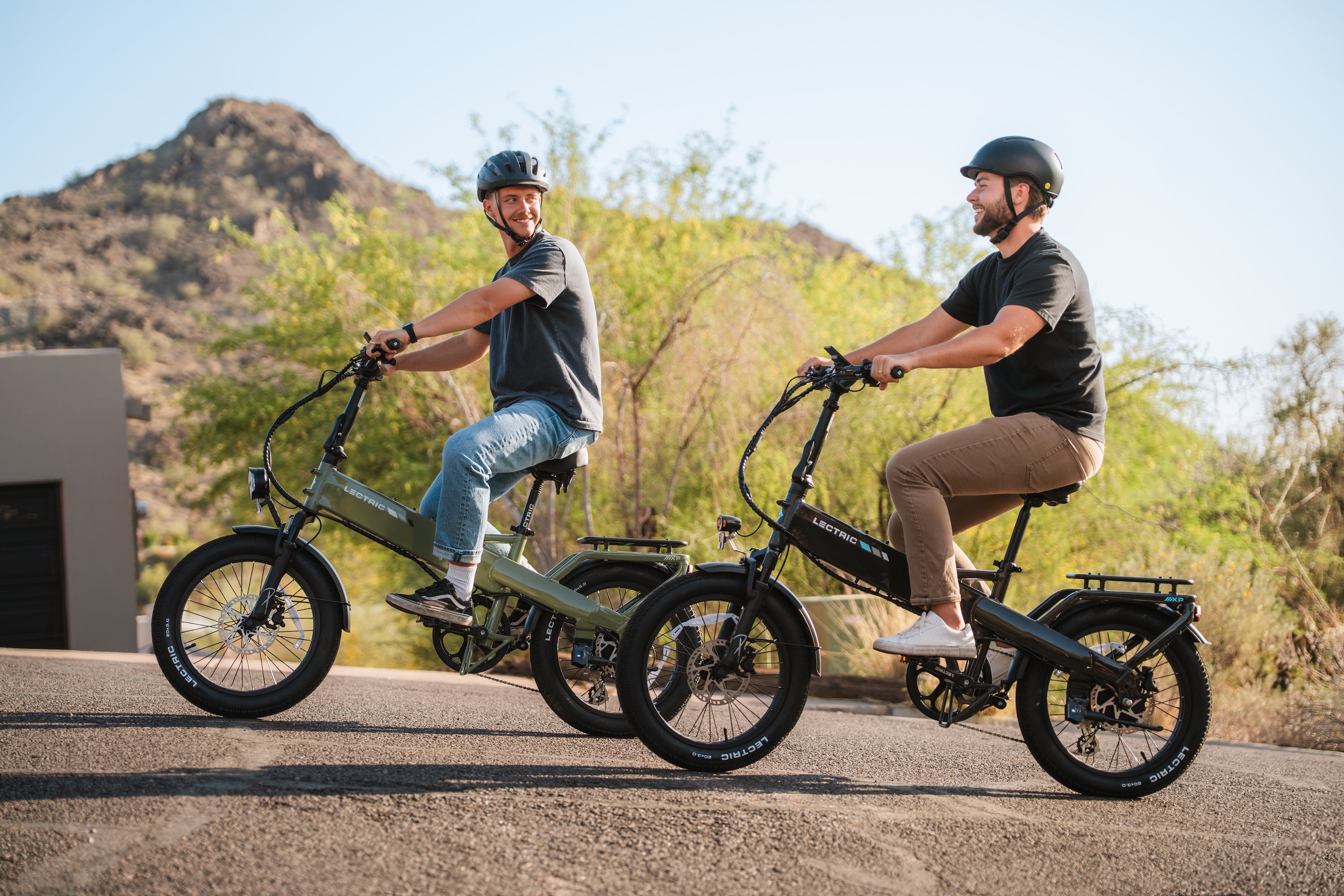 two men riding an ebike on a hill smiling