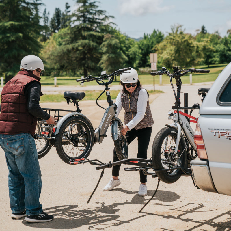 Un couple enlève un Lectric XP Trike sur un support à vélos attaché à leur VUS