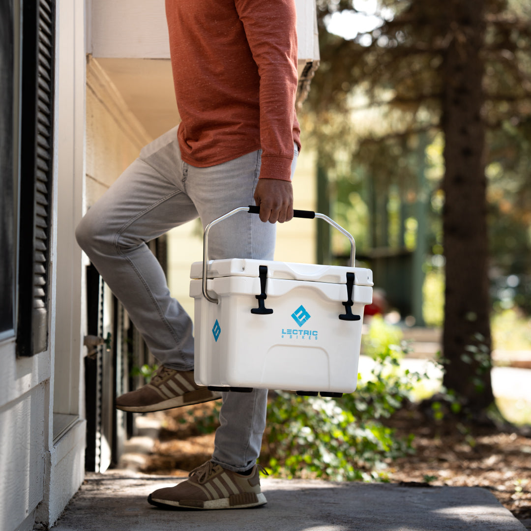 Un homme tenant la glacière Lectric Hard Cooler par la poignée rembourrée et l'emportant chez lui